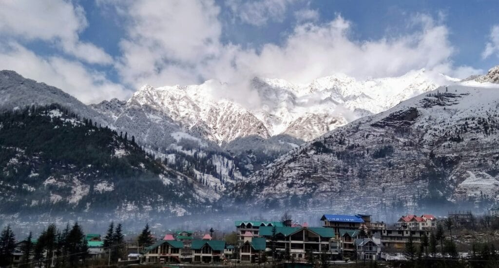 Snow-covered mountains and colorful houses in Manali, Himachal Pradesh